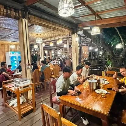 ລູກຄ້ານັ່ງກິນເຂົ້າໂຕະໄມ້ຍາວໃນຮ້ານອາຫານ