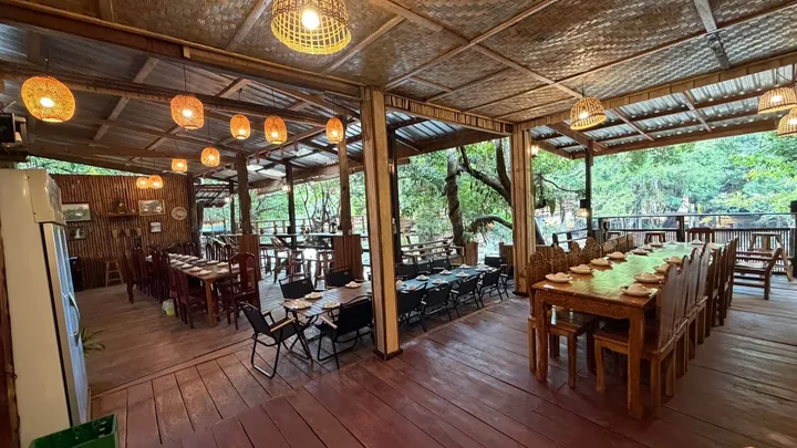 ໂຖງຮ້ານອາຫານເປີດໂລ່ງ ເຫັນຕົ້ນໄມ້ ແລະ ຫ້ວຍອ້ອມຮອບ