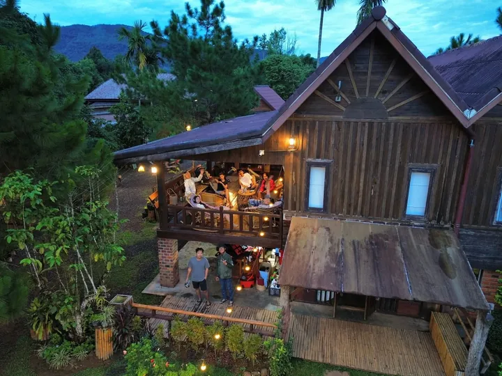 ເຮືອນໄມ້ຍາມຄໍ່າ ແຂກນັ່ງພັກຜ່ອນເທິງລະບຽງ